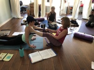 Yoga teacher training student learning how to do adjustments